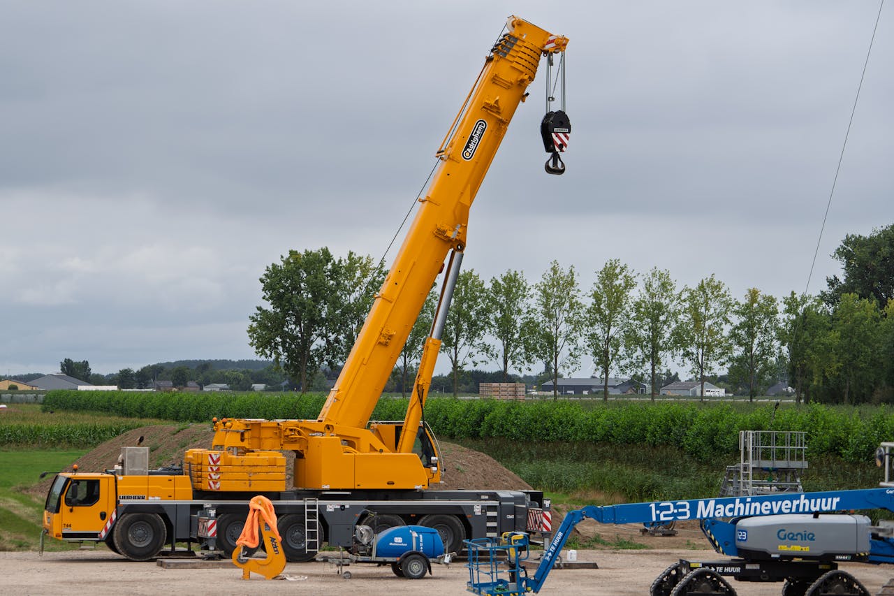 why-choose-us A large yellow crane at a construction site with lush greenery in the background.